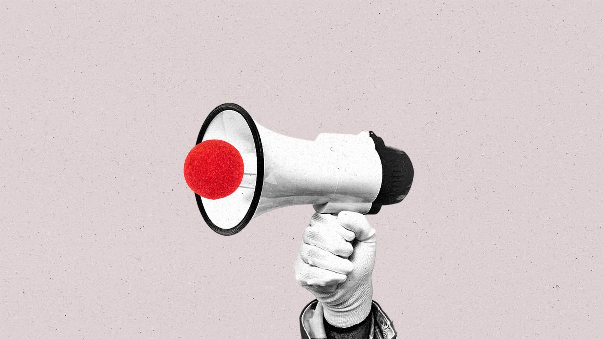 A hand holds a megaphone with a clown nose on it.