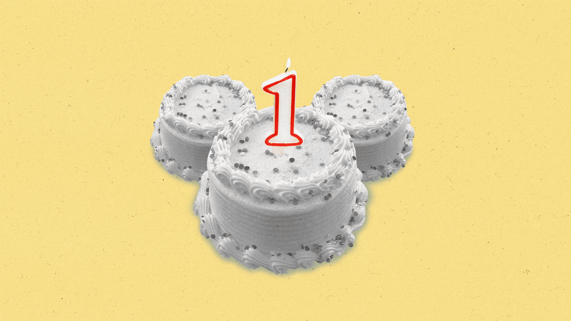 A black and white birthday cake in the shape of Mickey Mouse's head, with a number '1' candle on top.