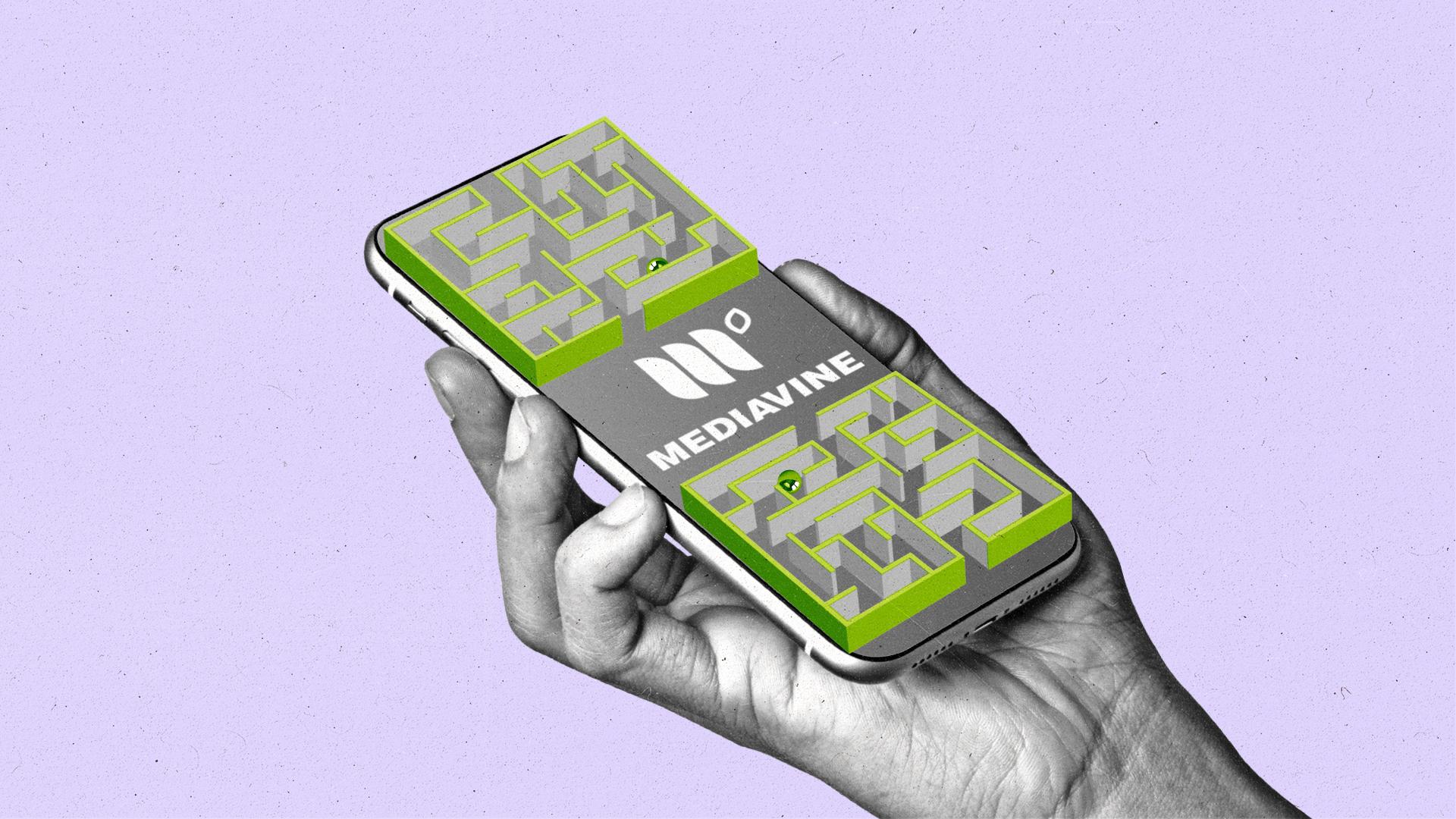 Hand holds a mobile phone with a maze on it and Mediavine logo in the middle of the maze.