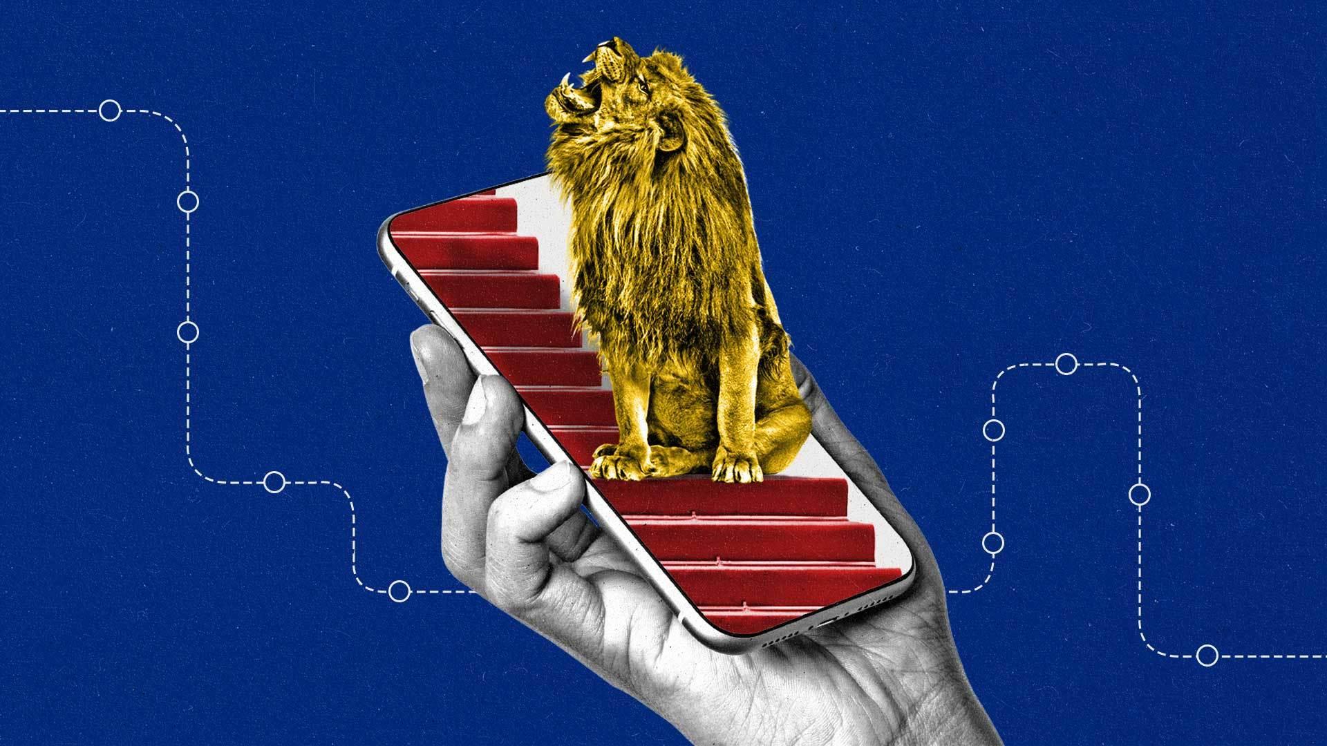 Hand holds phone with a gold lion on the screen sitting on red steps.