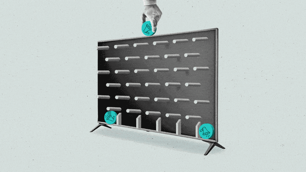 A hand places a puck down a connected TV, which moves downward like a plinko game to a bottom slot.