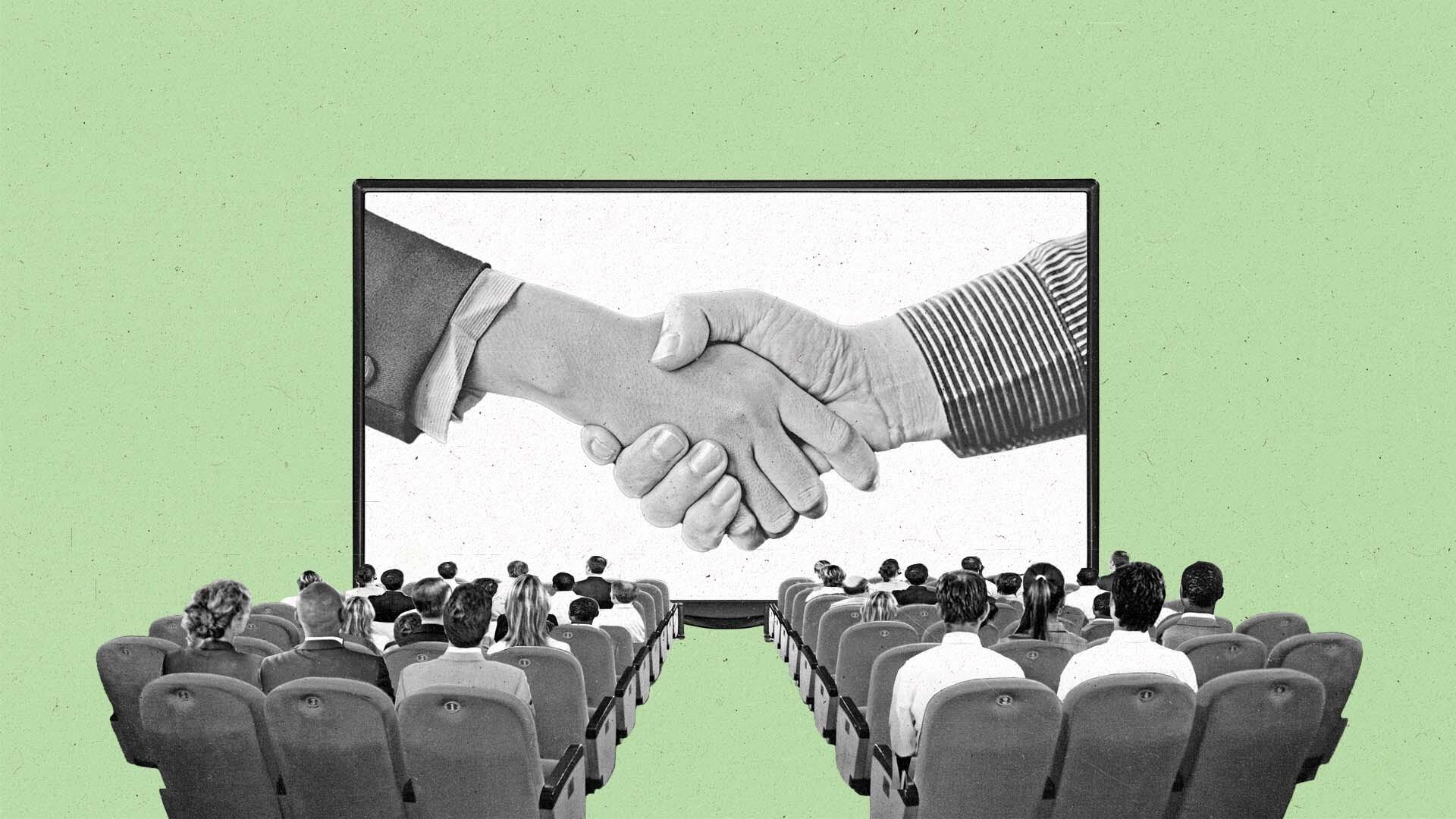 A seated crowd watches shaking hands on a connected TV.